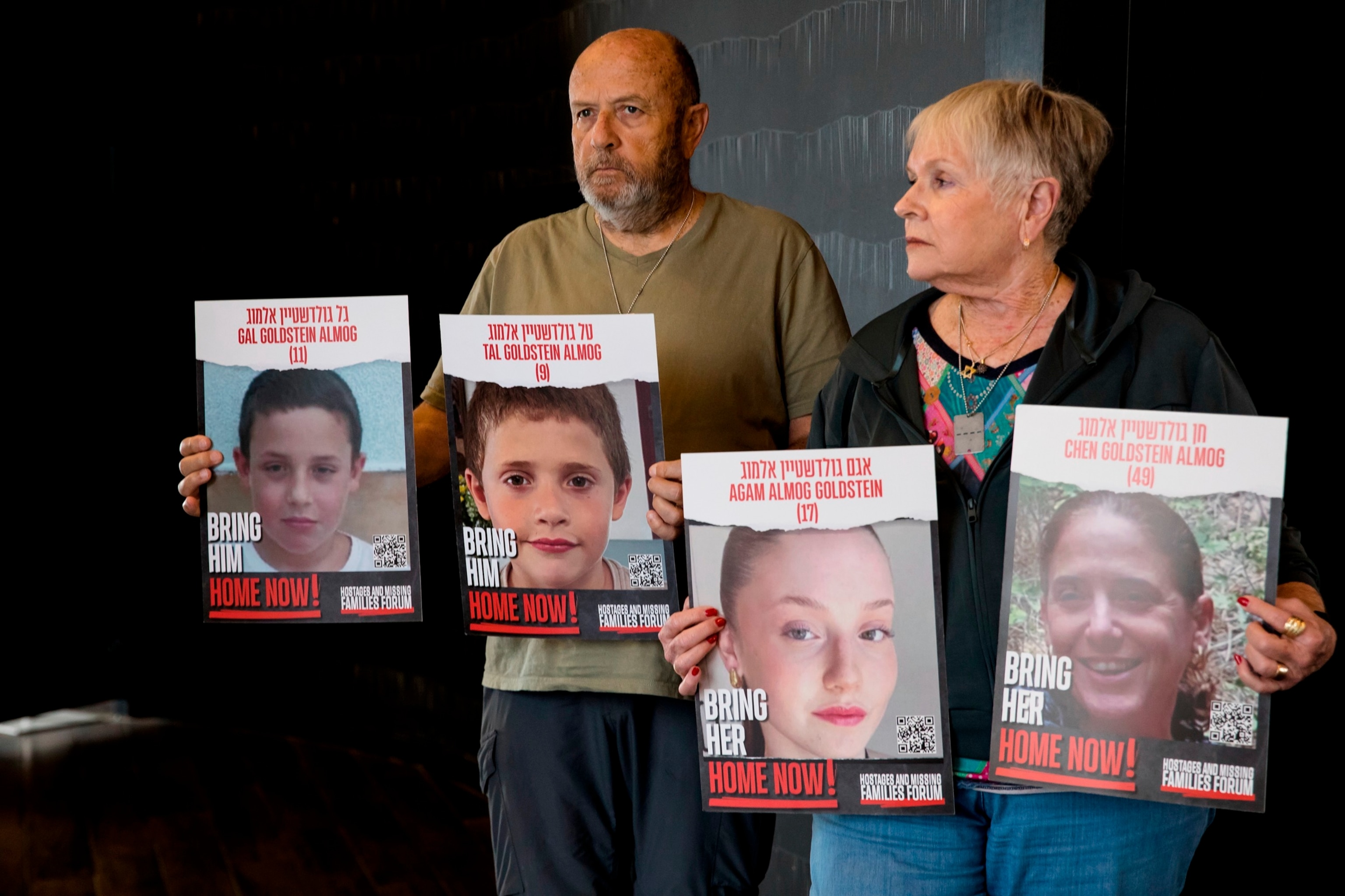 PHOTO: David and Varda Goldstein pose for a picture while holding-up photos of their 3 grandchildren, Gal, Tal and Agam as they await more details on the hostages deal in a hotel on Nov. 22, 2023, in Tel Aviv, Israel. 