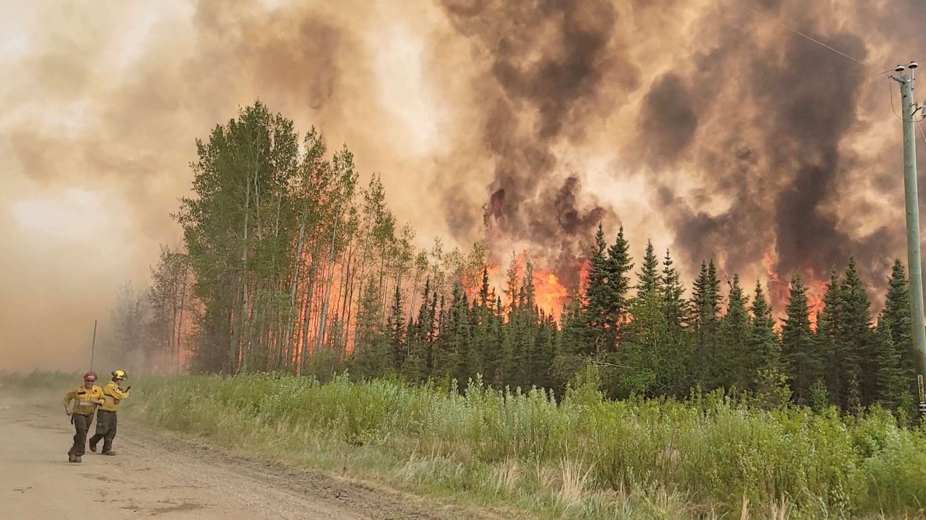 PHOTO: Firefighters retreat as flames approach, amid the Grizzly Wildfire Complex, in East Prairie Metis Settlement, Alberta, Canada, on May 19, 2023 in this still image obtained from social media video.