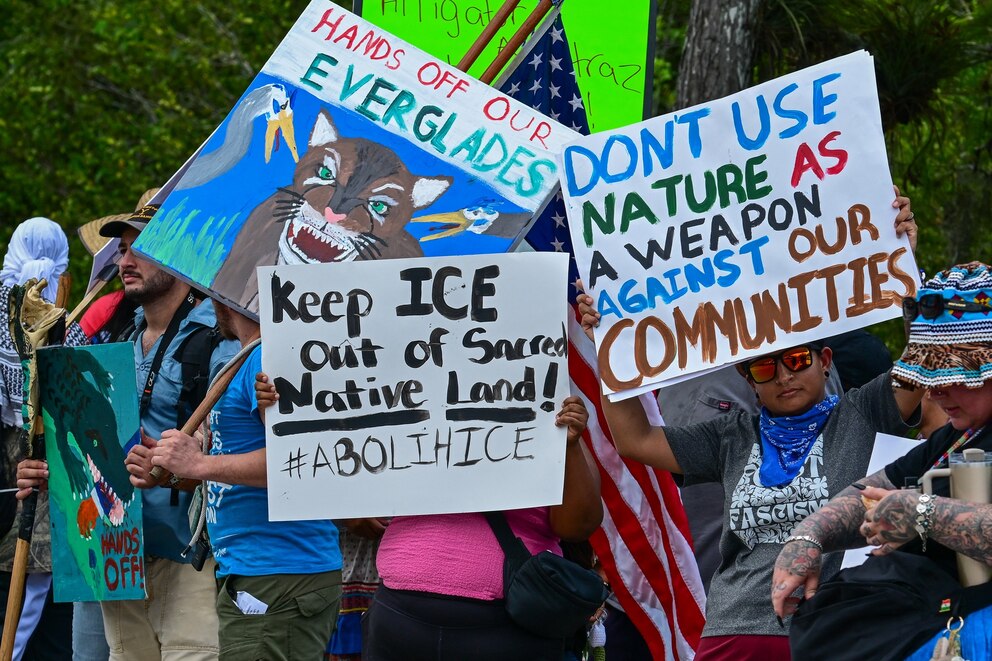 PHOTO: Demonstrators hold signs as they protest President President Donald Trump's visit to a migrant detention center, dubbed "Alligator Alcatraz," located at the site of the Dade-Collier Training and Transition Airport in Ochopee, Fla., July 1, 2025. 