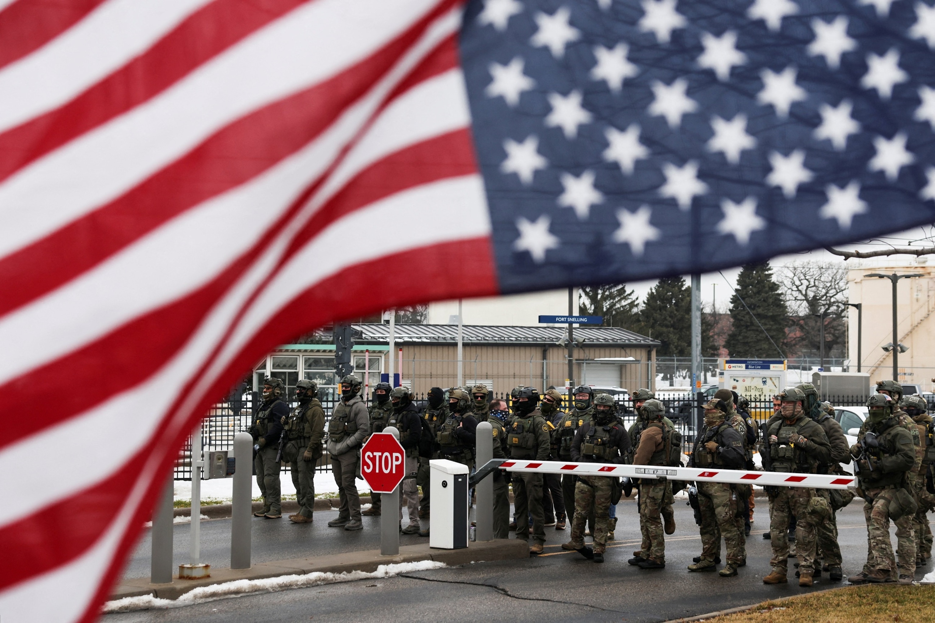 PHOTO: Homeland Security Investigations and Border Patrol stand guard, while an upside down U.S flag flutters, while demonstrators protest against the fatal shooting of Renee Nicole Good by an ICE agent in Minneapolis, Jan. 8, 2026. 
