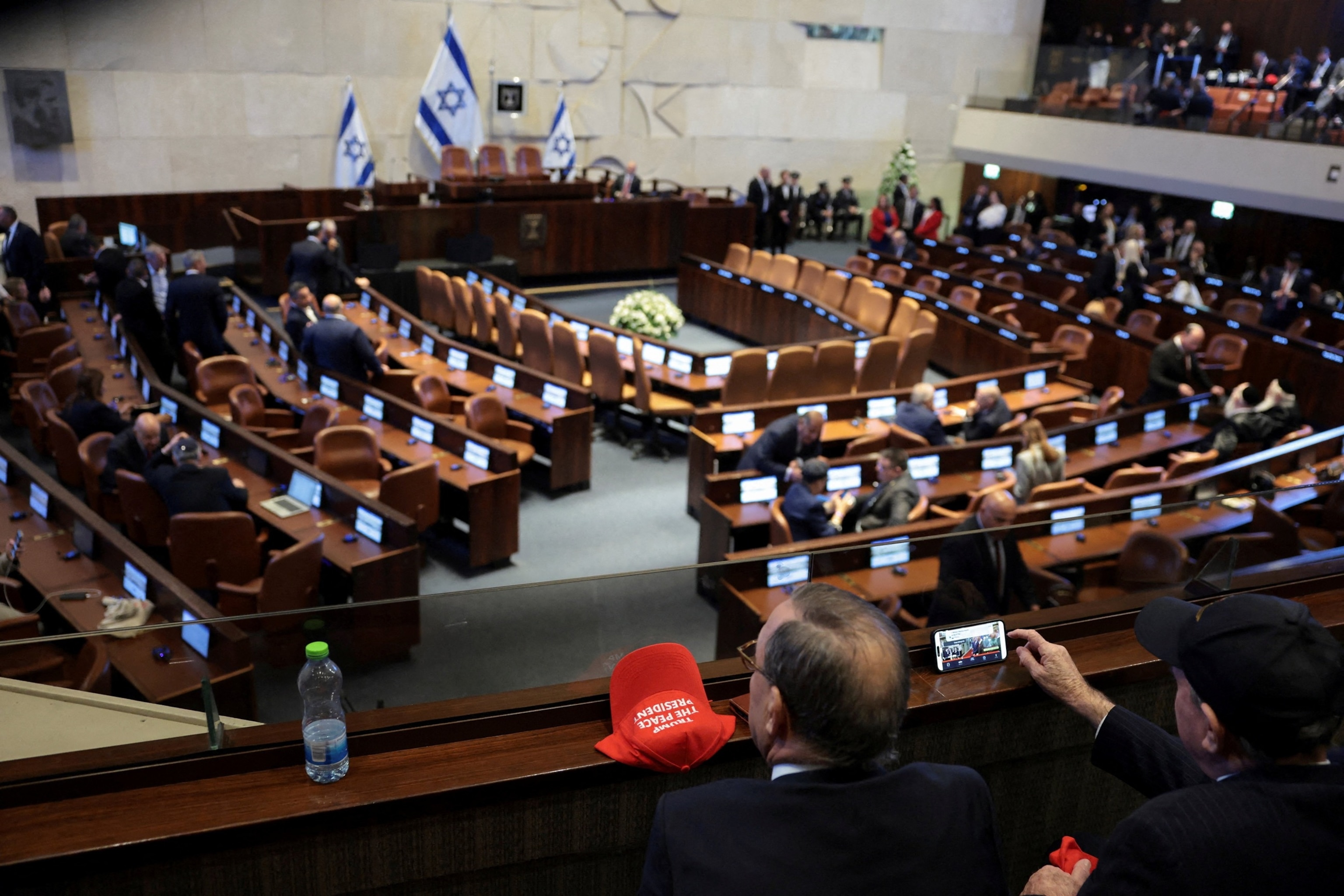 PHOTO: A man sits next to a cap with the words "Trump the Peace President," on the day U.S. President Donald Trump addresses the Knesset, in Jerusalem, October 13, 2025.