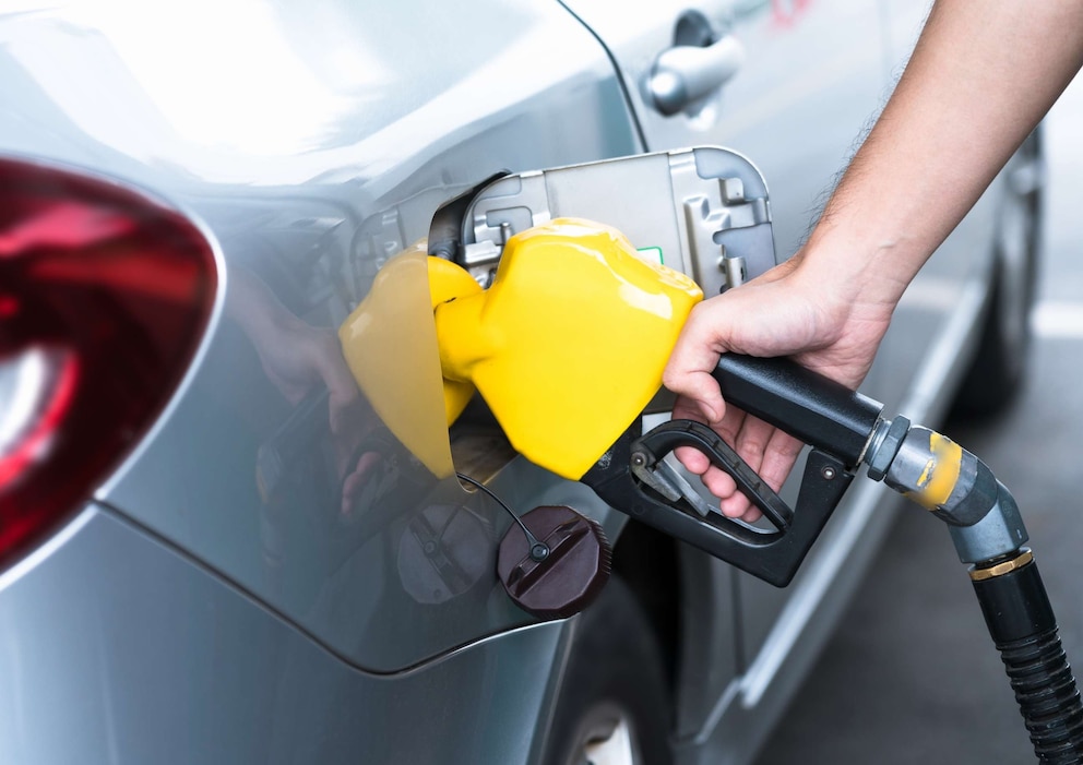 PHOTO: Hand refilling the car with fuel, close-up.