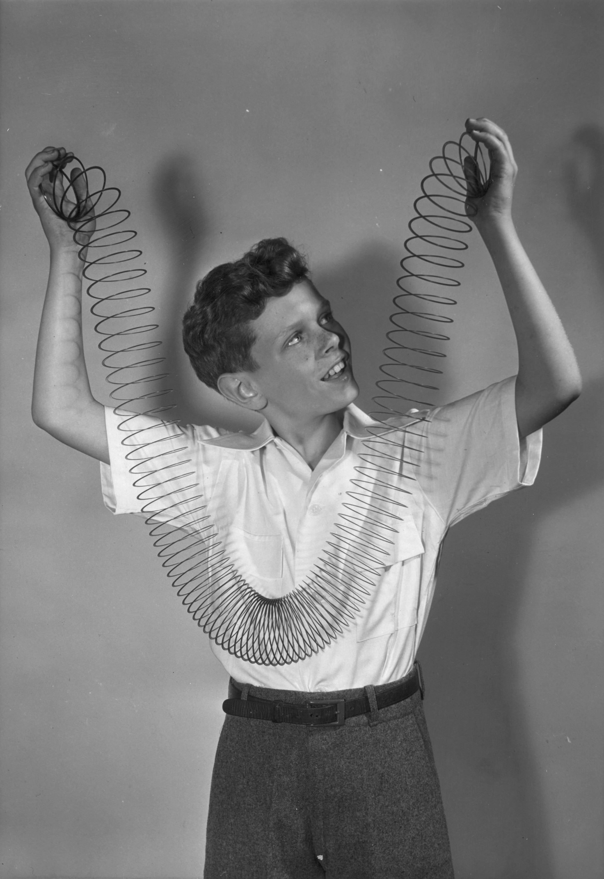 PHOTO: 14th June 1946:  A boy holds up a 'slinky'. Made of a coil of wire which if straight would be 75 feet long a 'slinky' will 'climb' down a flight of stairs when coiled up and positioned correctly.