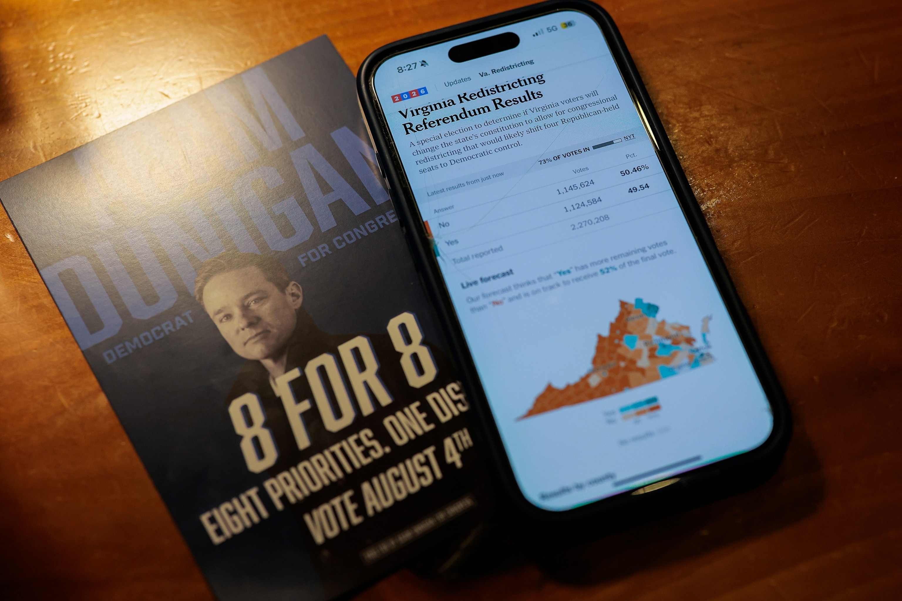 PHOTO: A local resident's phone screen is illuminated with updates of Virginia's congressional redistricting vote during a watch party at Inca Social on April 21, 2026 in Arlington, Virginia.