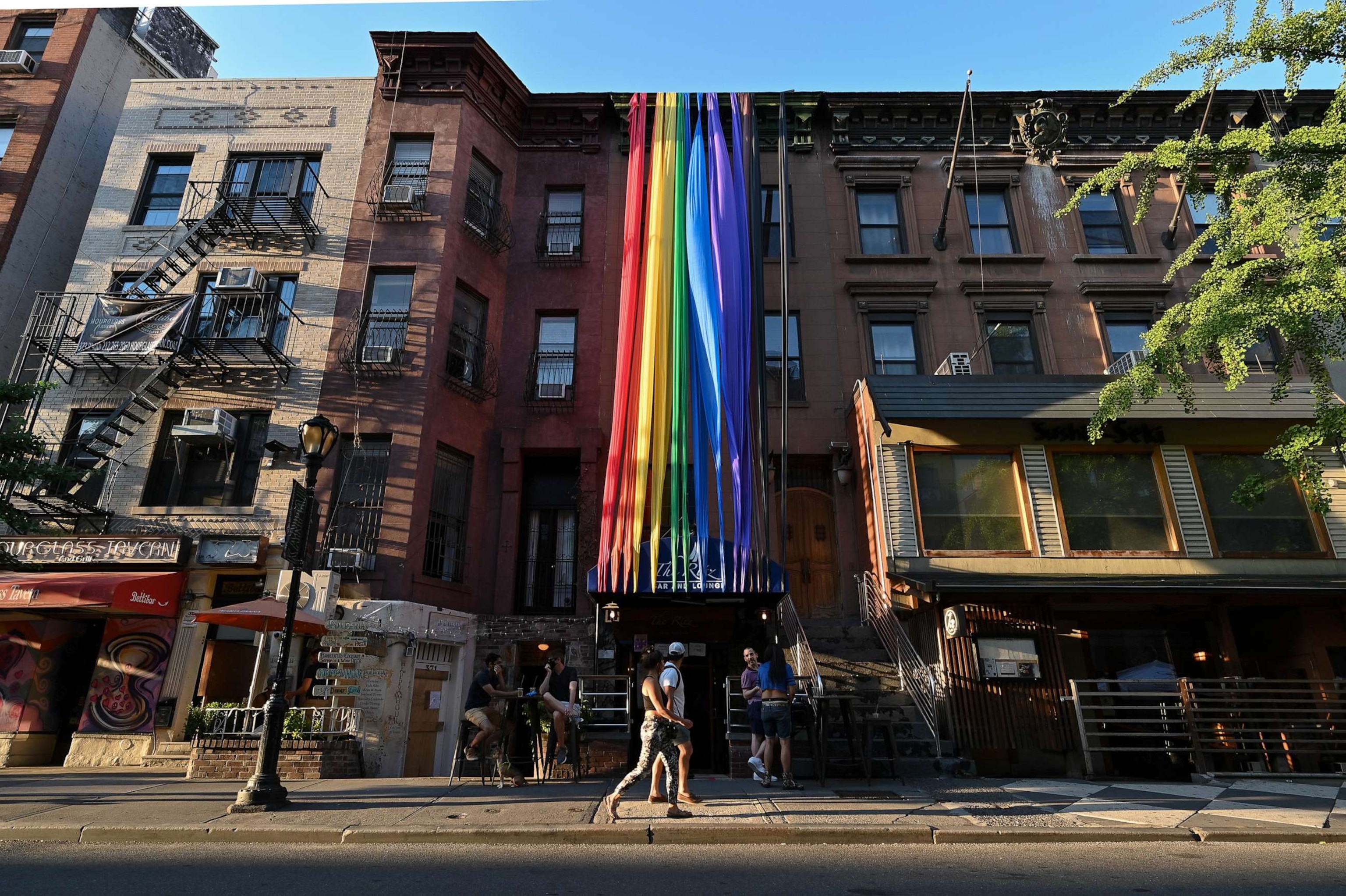 PHOTO: People walk past customers sitting at tables outside the Ritz Bar and Lounge in Hell's Kitchen, June 22, 2020, in New York.